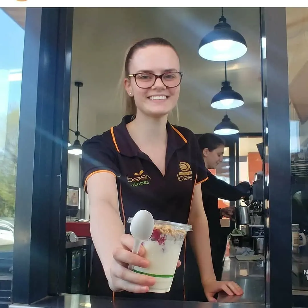 A barista handing a drink through the window