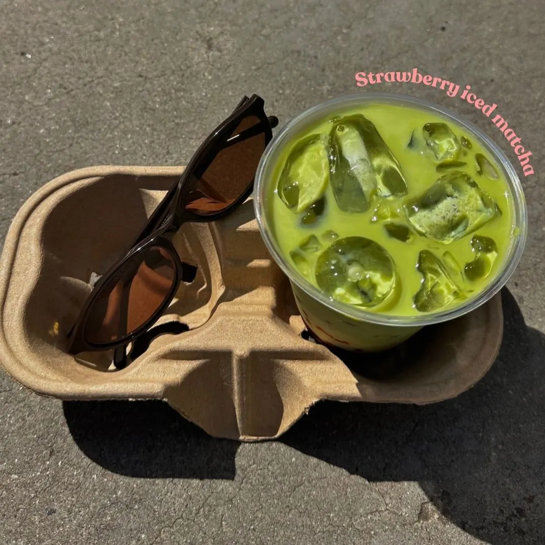 Strawberry iced matcha, made fresh daily, in a cup holder on a sunny day